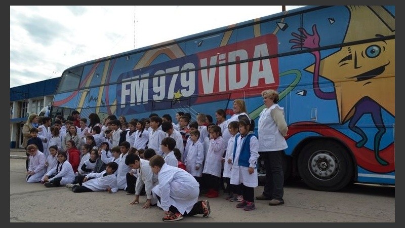 Los chicos de escuelas y docentes posan frente al micro ploteado con los colores de la FM VIDA.