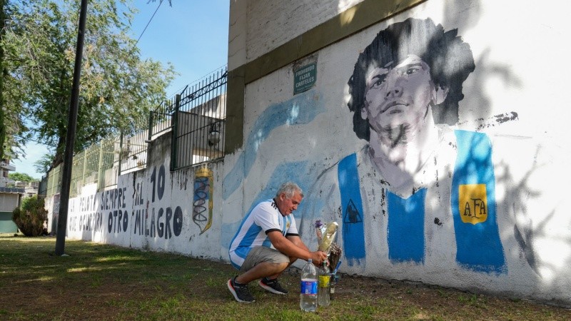 José le pone flores al mural de Maradona ubicado en Avellaneda y Santa Fe.