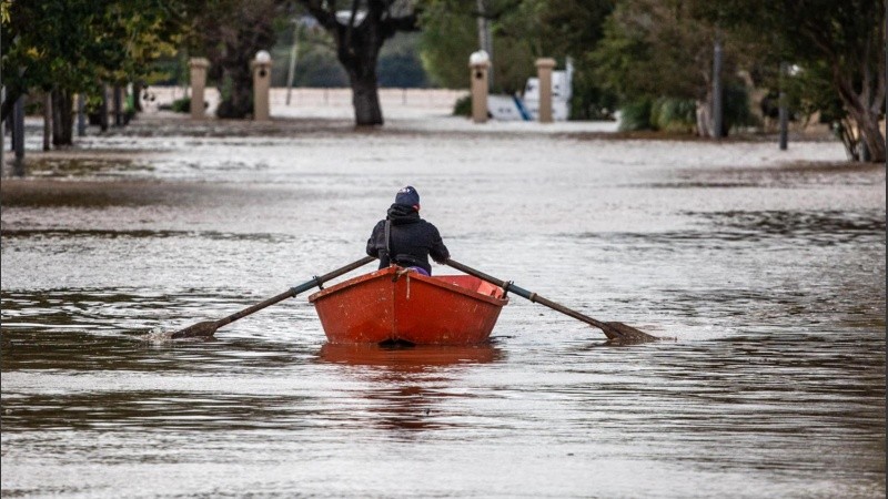 Un hombre conduce una embarcación por una calle inundada este lunes en Concordia.